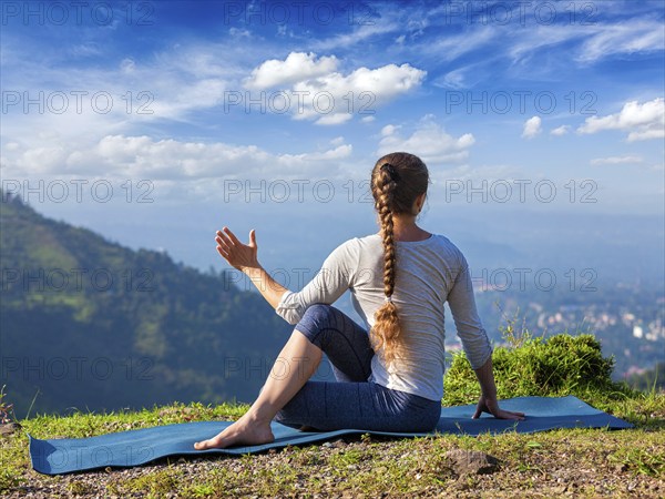 Hatha yoga outdoors, sporty fit woman doing yoga asana Parivrtta Marichyasana (or ardha