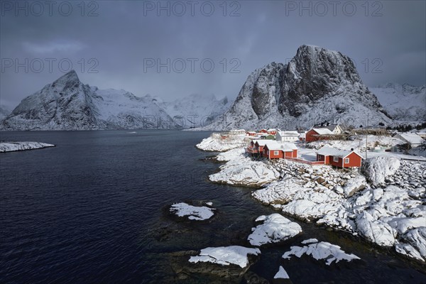 Iconic Hamnoy fishing village on Lofoten Islands, Norway with red rorbu houses. With falling snow