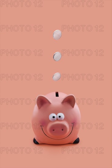 Pink piggy bank with coins falling down