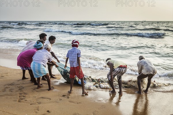 CHENNAI, INDIA, FEBRUARY 10, 2013: Indian fishermen dragging fishing net with their catch from sea