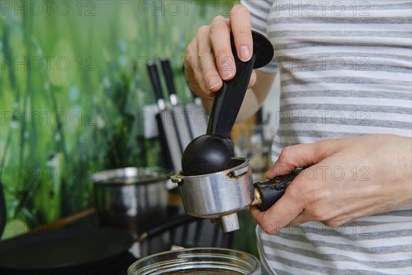 Closeup view of female hands making ground coffee in coffee machine