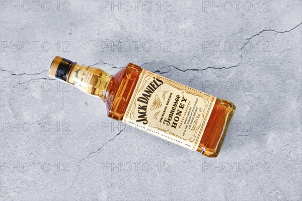 April 13, 2021, Minsk, Belarus, Bottle of Jack Daniel's Honey laying on cracked grey concrete