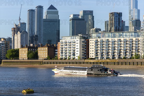 Uber boat water bus service passing Canary Wharf, Isle of Dogs, London, England, UK