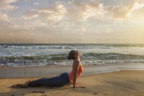 Yoga outdoors on beach, woman practices Ashtanga Vinyasa yoga Surya Namaskar Sun Salutation asana