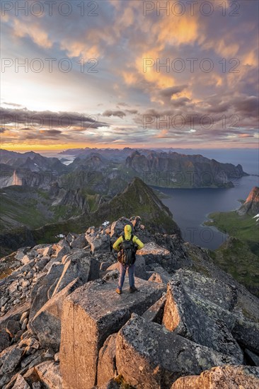 View over mountain top and sea, dramatic sunset, mountaineers at Hermannsdalstinden peak, with