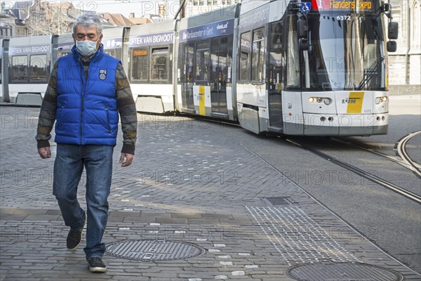Tram and man wearing medical face mask due to 2020 COVID-19, coronavirus, corona virus pandemic