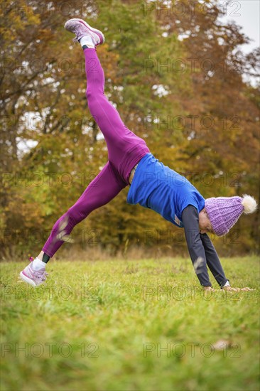 Fitness enthusiast woman practising handstand outside, surrounded by autumn colours, Gechingen,
