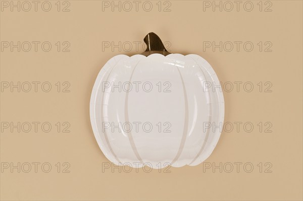 Simple pumpkin shaped party paper plate on beige background