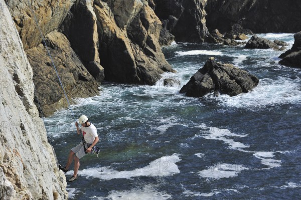Rock climber climbing cliff face at the pointe de Pen-Hir, Finistère, Brittany, France, Europe