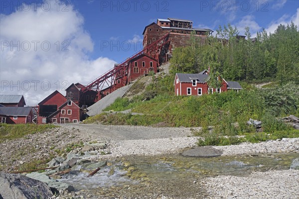 Crystal-clear stream and old industrial ruins on the hillside, copper mining, red wooden buildings,