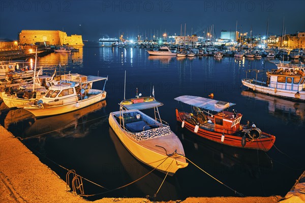 Venetian Fort castle in Heraklion and moored Greek fishing boats in port, Crete Island, Greece in