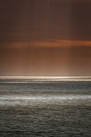 Sunbeams through cloud cover, sunlight glistening on the sea, evening sky, motion blur,