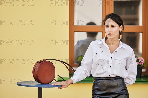 City portrait of elegant lady in leather skirt and white shirt with leather hand bag