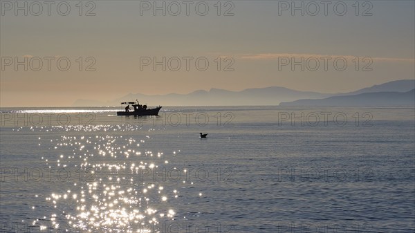 Fishing boat, glitter on the water, sunrise, morning light, Marettimo, Egadi Islands, Sicily,