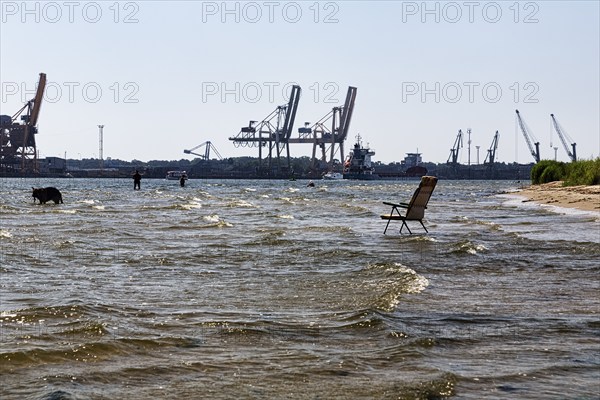 Garden chair in the water, symbol photo cooling off in summer, harbour entrance port city