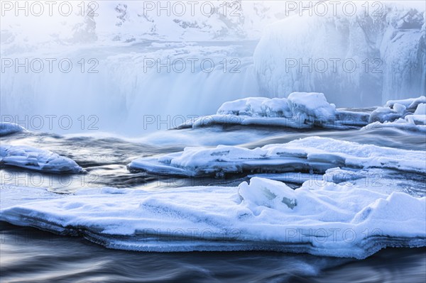 Icefall at the edge of the Godafoss waterfall at dawn, snow-covered landscape, Northern Iceland