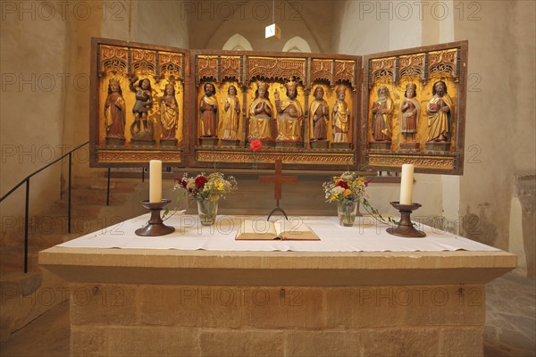 Interior view and folding altar with candles, bible and bouquet of flowers of the Romanesque