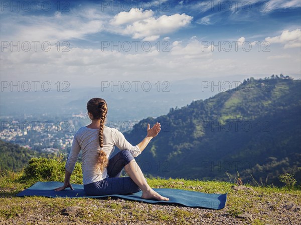 Hatha yoga outdoors, woman doing yoga asana Parivrtta Marichyasana (or ardha matsyendrasana),