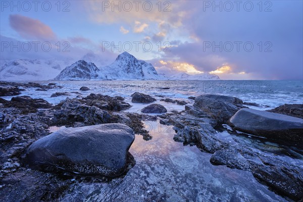 Beach of Norwegian sea on rocky coast in fjord on sunset in winter. Vareid beach, Lofoten islands,
