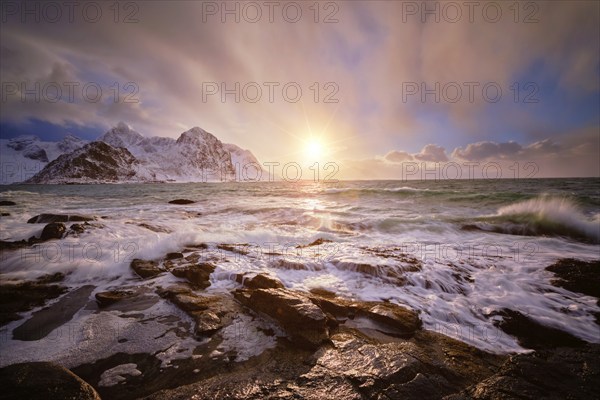 Beach of Norwegian sea on rocky coast in fjord on sunset in winter. Vareid beach, Lofoten islands,