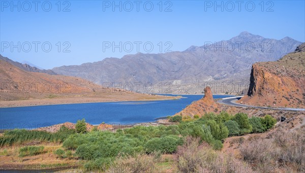 Blue Toktogul reservoir between dry mountain landscape with red mountains, Jalalabad region,