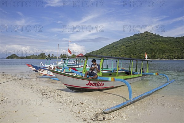 Indonesian tourist guide playing ukulele on outrigger boat on the islet Gili Nanggu, Gili Islands,