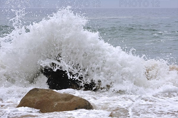 Wave crashing into boulder in the surf at the Côte Sauvage, Wild Coast, Quiberon, Brittany, France,
