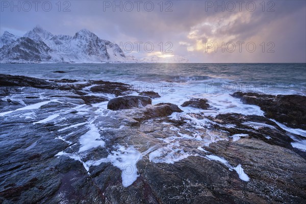 Beach of Norwegian sea on rocky coast in fjord on sunset in winter. Vareid beach, Lofoten islands,