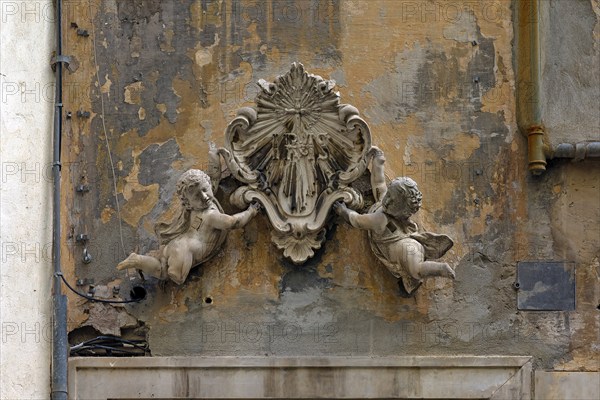 Putti holding an ecclesiastical symbol above an entrance door to a crypt, historic centre, Piazza