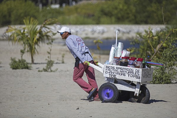 Beach vendor pulling cart with drinks at Playa Principal near Puerto Escondido, San Pedro Mixtepec,