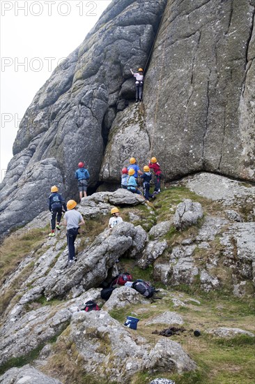 Children rock climbing on the granite tor of Haytor, Dartmoor national park, Devon, England, UK