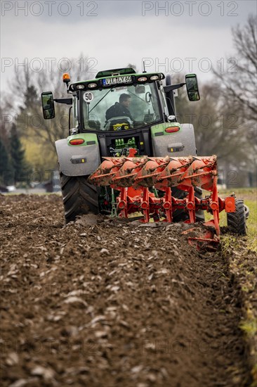 Tractor with a plough preparing the soil of a field for planting, Agriculture, Spring