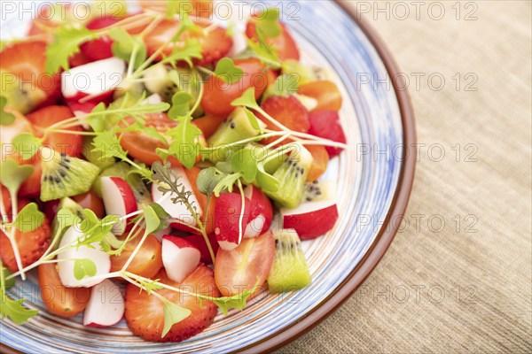 Vegetarian fruits and vegetables salad of strawberry, kiwi, tomatoes, microgreen sprouts on black