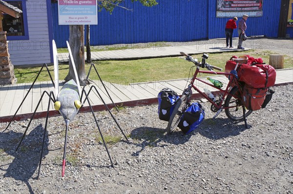 Bicycle with luggage next to an oversized mosquito, Carcross, Yukon Territory, Canada, North