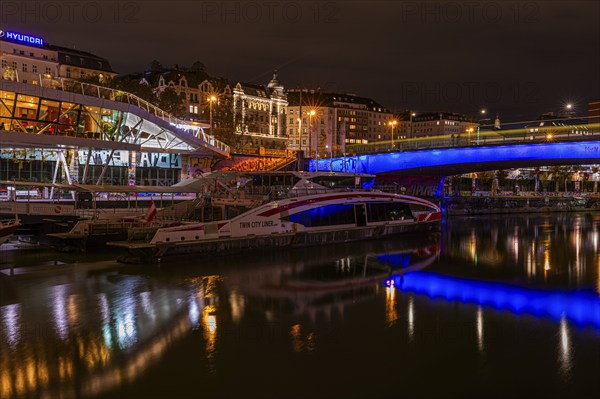 Ferry anchored in the Danube Canal, behind the illuminated Franz-Josefs Quay and St Mary's Bridge,