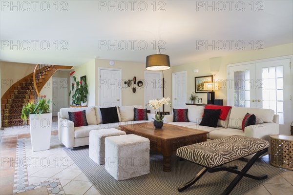 Beige upholstered sofas with colourful cushions, wooden coffee table and zebra motif ottoman in