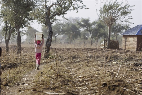 Girl carrying a heavy bucket of water on her head, Maraban Dare, 07/02/2024