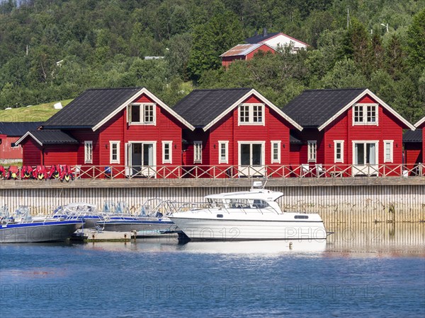 Typical red-white wooden holiday cottages, pier with leisure boats, Lenangsstraumen, Lyngen
