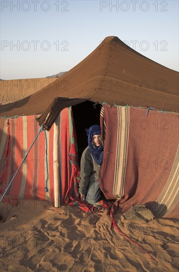 Model Released Young tourist boy dressed with blue nomad head scarf kneels at the entrance to a