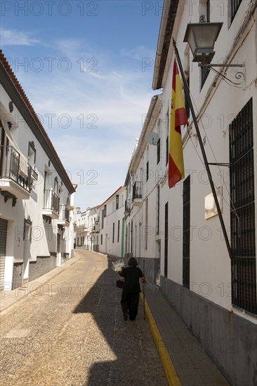 Woman walking along a quiet street in village of Jabugo, Sierra de Aracena, Huelva province, Spain,