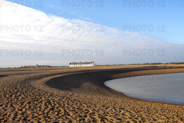 Frontal clouds passing over Coastguard Cottages shingle beach at Shingle Street, Suffolk, England,