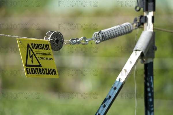 Electric fence on a pasture, warning sign, electric shock