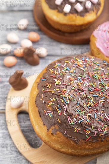 Homemade glazed and decorated easter pies with chocolate eggs and rabbits on a gray wooden