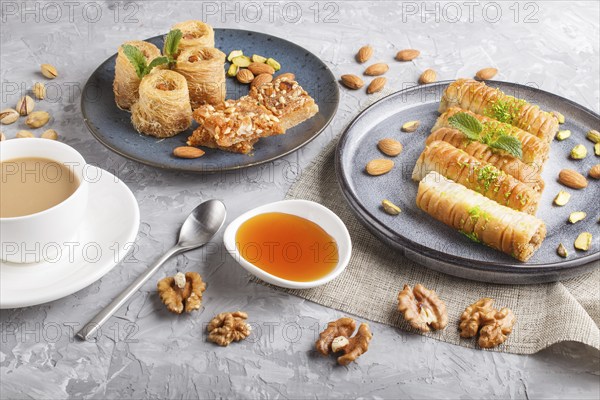 Set of various traditional arabic sweets: baklava, kunafa, basbus in ceramic plates on a gray