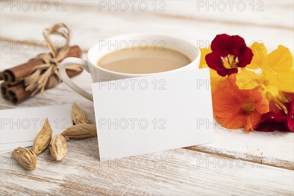 White paper business card mockup with orange nasturtium flower and cup of coffee on white wooden