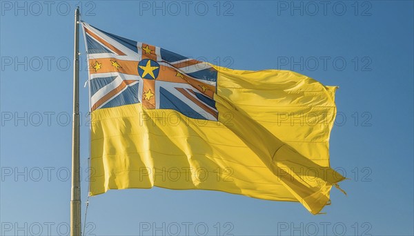 The flag of Niue, an island state in the Pacific Ocean, flutters in the wind, isolated against a