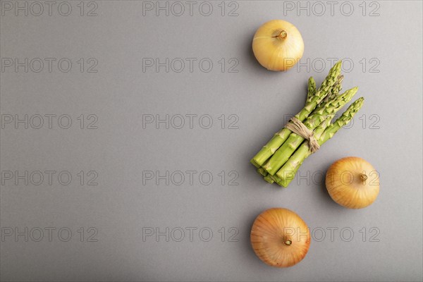 Bunch of fresh green asparagus and onion on gray pastel background. Top view, flat lay, copy space.