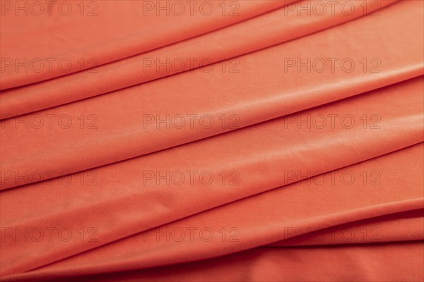 Fragment of red silk tissue. Side view, natural textile background and texture. wave concept,