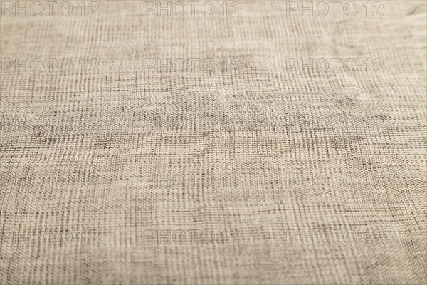 Fragment of smooth brown linen tissue. Side view, natural textile background and texture
