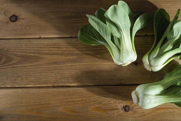 Fresh green bok choy or pac choi chinese cabbage on a brown wooden background. Hard light, contrast